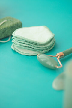 Cotton pads and jade roller on turquoise background