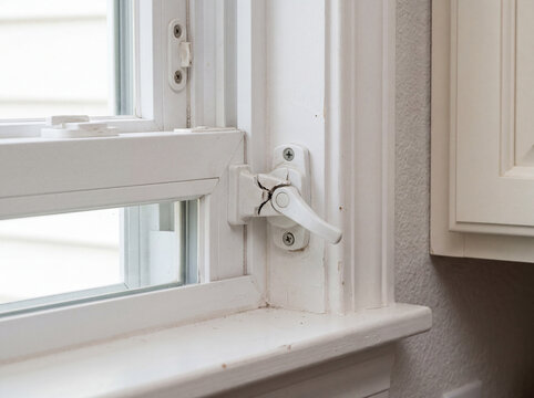 Broken white window crank handle on a residential window frame