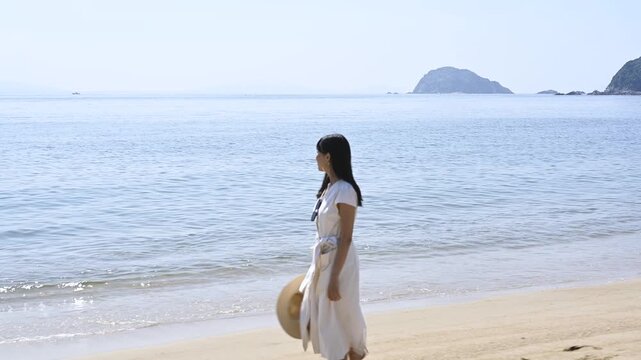 海の砂浜を散歩する女性