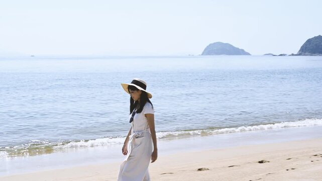 海の砂浜を散歩する女性