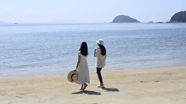 海の砂浜を散歩する女性２人