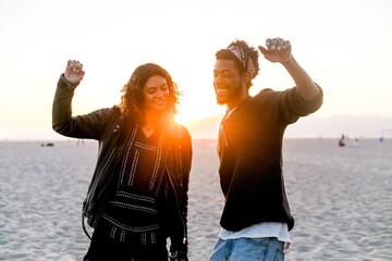 Joyful friends dancing sunset beach