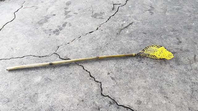 Traditional handmade bamboo fish net on a cracked concrete surface