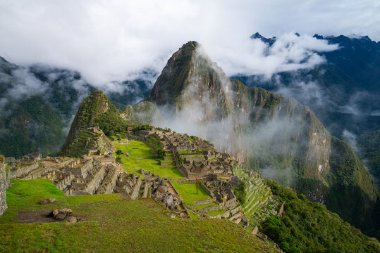 Early morning sunny blue sky low clouds fog Machu Picchu Historic Sanctuary Temple rainy season Inca citadel Eastern Cordillera of southern Peru Incan citadel Peruvian Andes Mountains landscape pano