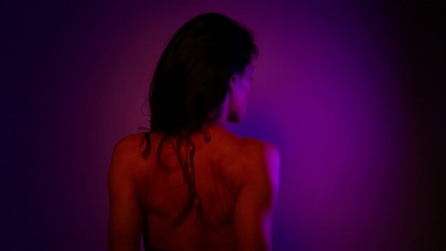 Beauty dancer woman shaking her long hair dancing in a dark studio colorful glows in fantasy club neon with red blue purple lights. Magic blending with sexy body girl. Art creative expression video