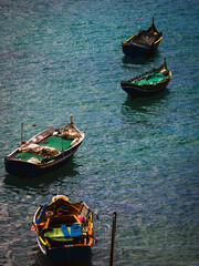 Obraz premium Traditional colorful fishing boats floating on turquoise Mediterranean sea water