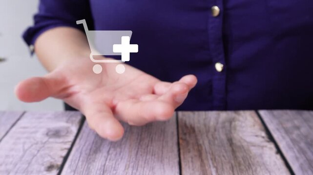 Close-up of a woman's hand on a table holding an animated shopping icon with the add-on button. Add more products to your cart.