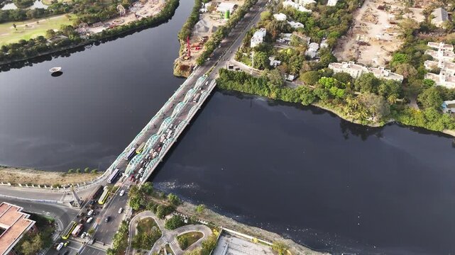 Aerial of Napier Bridge, Chennai, showing cars and buses crossing the historic pollutated Coovam River. The composition emphasizes geometry, traffic patterns, and the city&rsquo;s coastal infrastructure.