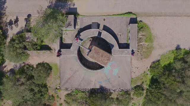 Top down drone shot over 7&ordf; Bataria de Costa in Arrabida Portugal showing a man rotating one of the abandoned cannons with surrounding historic structures.