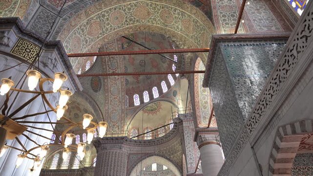 A wide shot showcases the massive "elephant foot" columns and grand arches of the Blue Mosque in Istanbul, Turkey. A stunning view of Ottoman architectural mastery and scale.