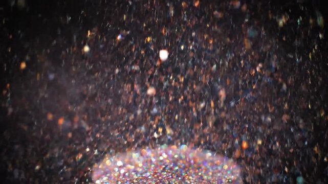Vibrant glitter particles explode upwards and fall against a dark background