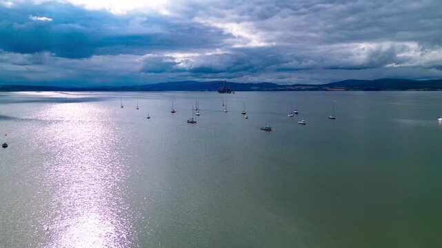 Drone footage of numerous boats anchored off the coast of Cromarty along the Cromarty Firth, showcasing a peaceful maritime setting and coastal lifestyle in the Scottish Highlands.
