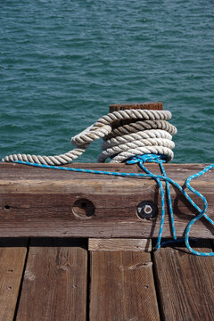 Heavy rope tied around a wooden post on a harbor pier