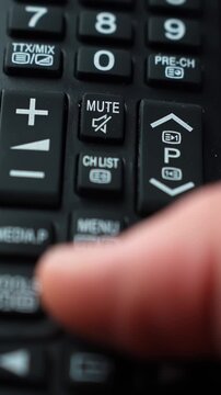 Macro shot of a finger pressing the up arrow on a TV remote near mute and channel list keys, shallow depth of field and soft indoor light for a clean tech navigation moment.