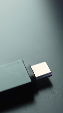 Macro shot of USB-C to USB 3.0 adapter on dark desk with soft bokeh and lots of copy space, modern minimal tech vibe in vertical frame.
