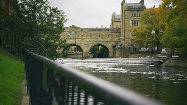 Low angle view of Pulteney Bridge and the River Avon in Bath Somerset with water flowing over the historic weir on an overcast day in England