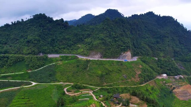 4K drone orbit revealing panoramic serpentine roads on the mountainside with small ethnic villages at the foot of the valley in Ha Giang.
