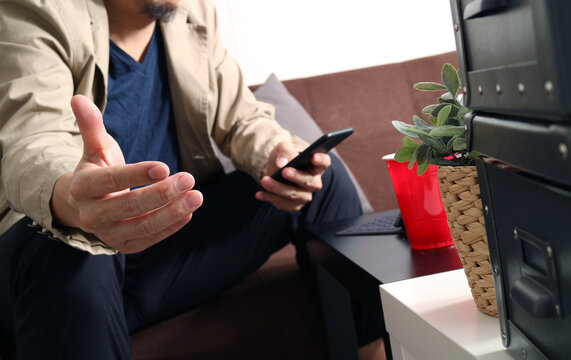Man Using Smartphone While Relaxing on Sofa at Home
