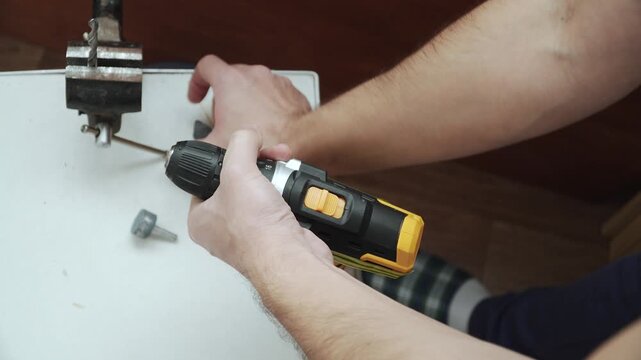 Changing grinding attachments of different shapes in self tightening chuck of screwdriver in home workshop. Process of preparing for grinding and turning metal parts and sharpening drill.