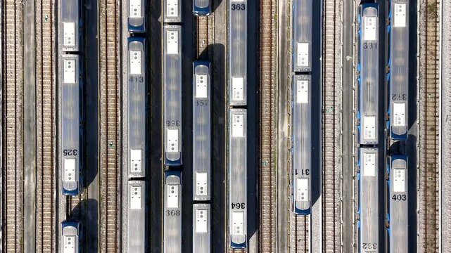Top down aerial view of numerous passenger metrorail wagons parked on multiple tracks at a large depot