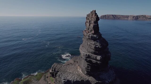 edimentary sandstone sea stack shaped by differential marine erosion standing offshore along Atlantic coastline of Vila Nova de Mil Fontes Odemira Alentejo Portugal with visible horizontal bedding
