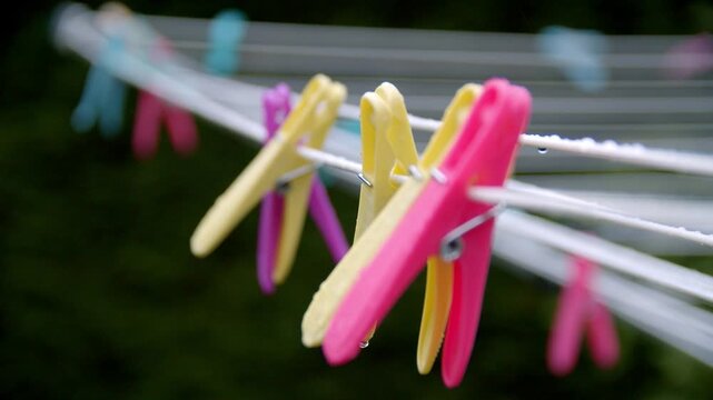 Pull focus on a wet clothing line of coloured pegs in early morning light