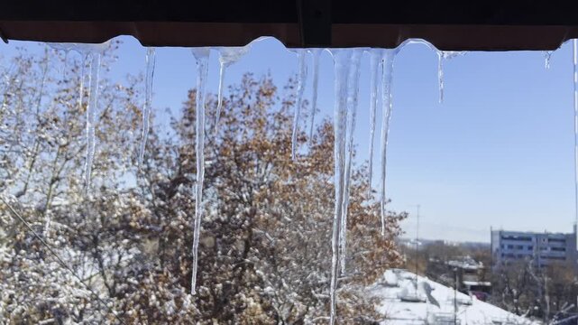 Close-Up Icicles Above Window With Winter Sky and City Background