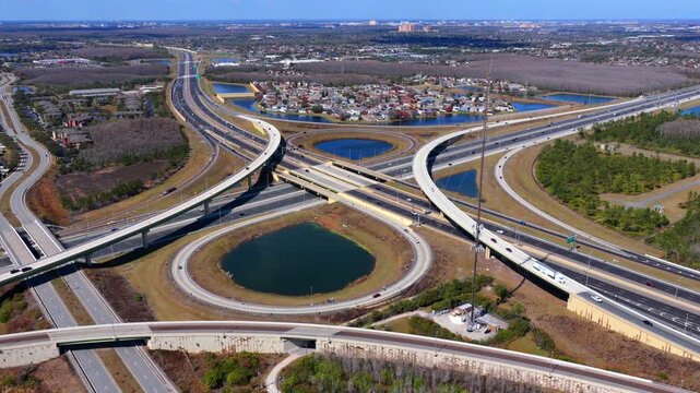 An aerial view of a large stack interchange on Florida's Turnpike on a sunny day. The camera tilted downward, truck right and pan left over the highway intersection and bodies of water.