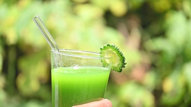 Bitter gourd or bitter melon juice on a blurry green background. This emerald tonic is celebrated in traditional medicine for its ability to regulate blood sugar and detoxify the body.