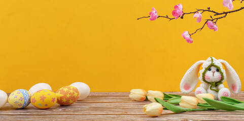 Fototapeta premium Easter bunny and eggs with tulips on yellow background