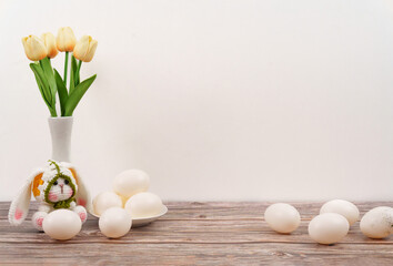 Fototapeta premium Easter bunny with tulips and white eggs on wooden table