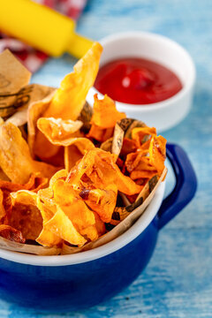 Crispy vegetable chips served with ketchup on blue table