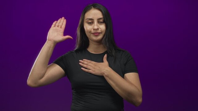 Woman with right hand on chest and left palm raised in studio against deep purple backdrop; sincerity.