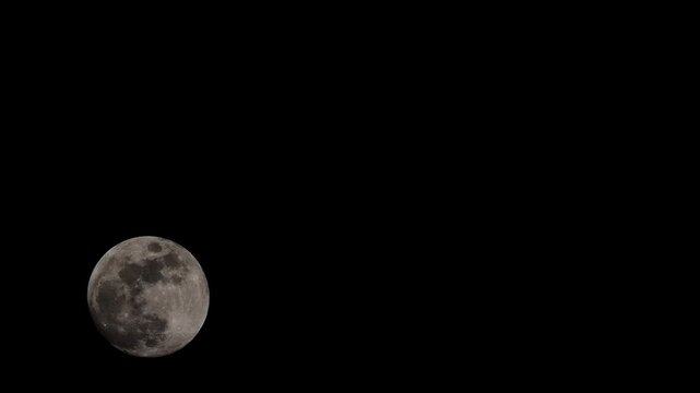 Moon at nearly full size rising in spring being passed over by cloud and disappearing.