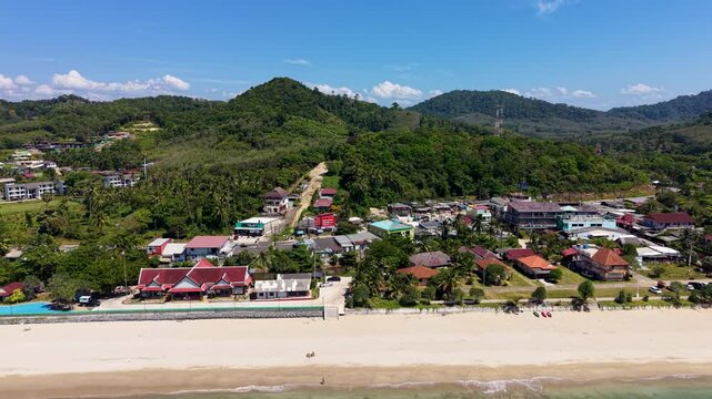 Experience a stunning aerial view of Klong Nin Beach on Koh Lanta Island, Thailand. The drone footage captures a picturesque coastline with lush greenery and vibrant shoreline under clear blue skies.