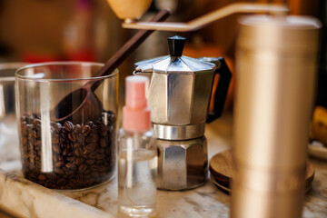 Ingredients for making coffee. Moka pot, bean spray, coffee grinder with coffee beans standing on the kitchen table.