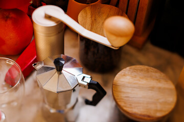 Ingredients for making coffee. Moka pot, bean spray, coffee grinder with coffee beans standing on the kitchen table.