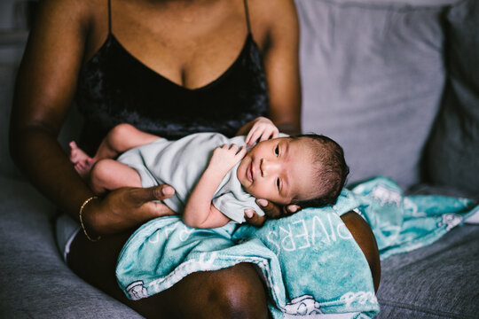 Mom holding newborn baby boy with blanket at home with love