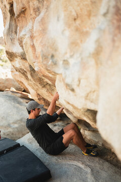 Young climber in starting position to boulder on monzogranite rock