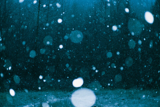 Snowflakes fall against dark background in storm