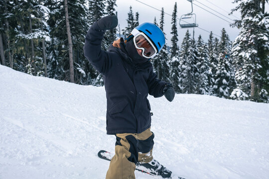 Young boy skiing puts his hands up in excitement at Whistler