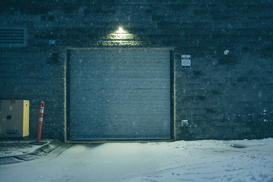 Garage door at night surround by snow and falling snow flakes
