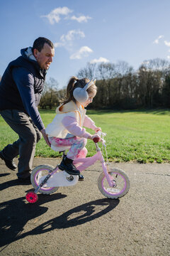 Father teaching his daughter riding a bicycle in the park