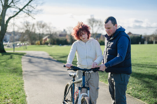 Father teaching his teenage girl riding a bicycle in the park