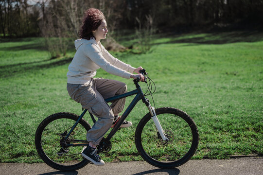 Teenage girl riding a bicycle in the park, spring time, copy space