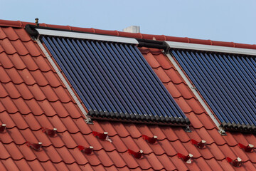 Solar thermal collectors installed on a red-tiled roof in a sunny environment promoting renewable energy use