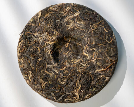 Unique disc of pressed tea leaves on a plain surface surrounded by natural light in a simple setting