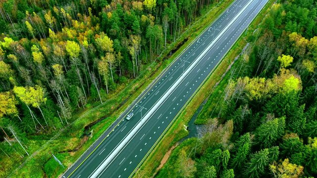 Aerial View of a Serene Highway with driving cars and truck Surrounded by Lush Green Forest
