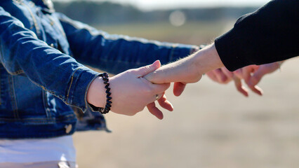 Couple holding hands with fingers interlocked, walking in trust and support