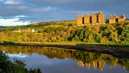 Scenic landscape featuring a building complex atop a tree-lined embankment mirroring in calm waters